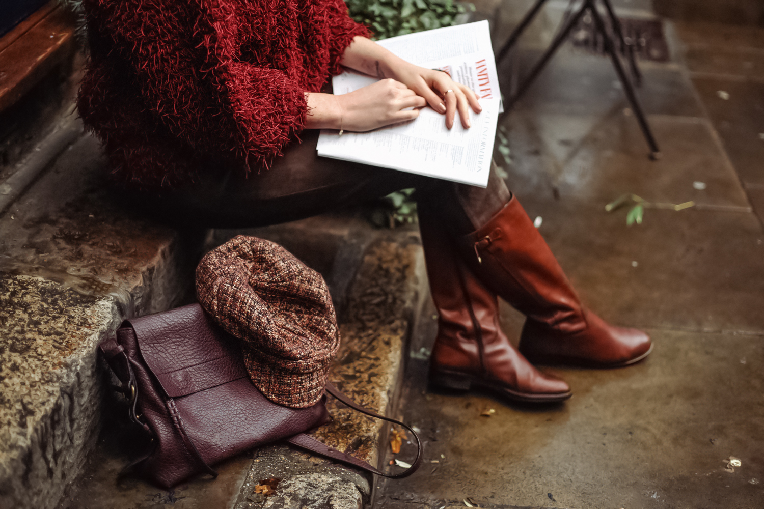 woman in fall outfit is sitting on the stairs with a book in her arms