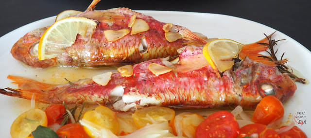 Salmonetes al horno, aromatizados con limón, hierbas aromáticas y ajo, acompañados de una guarnición horneada de cebolleta y tomates cherryes