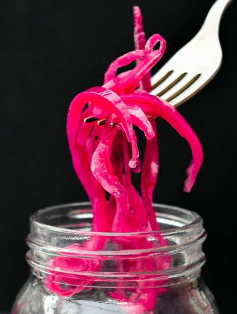 Quick pickled onions lifted out of glass jar with a fork