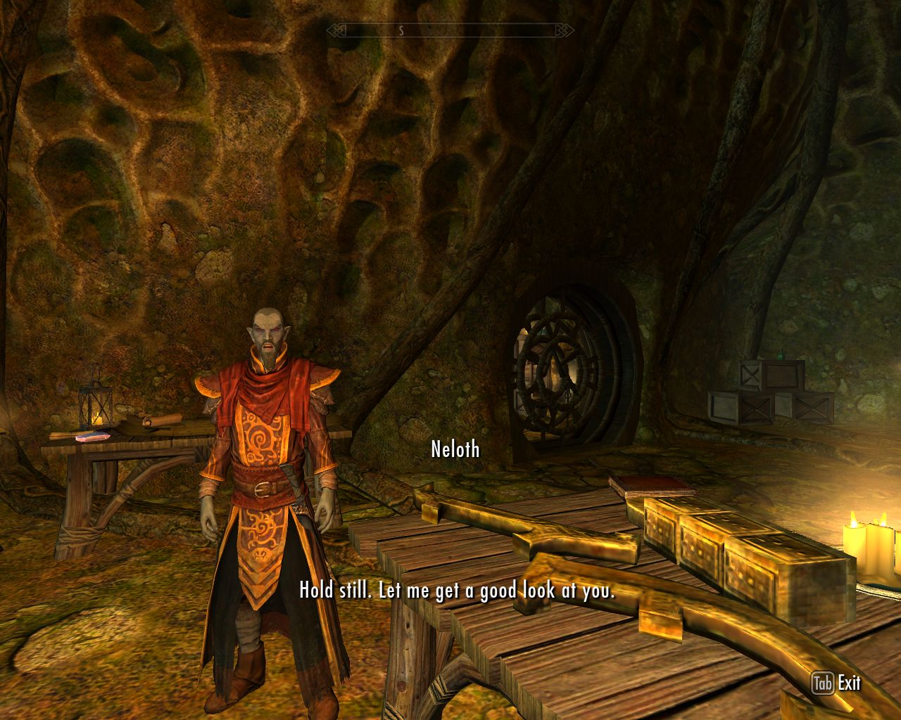 Neloth talks to the protagonist in his house, objects of dark yellow metal on a table in the foreground