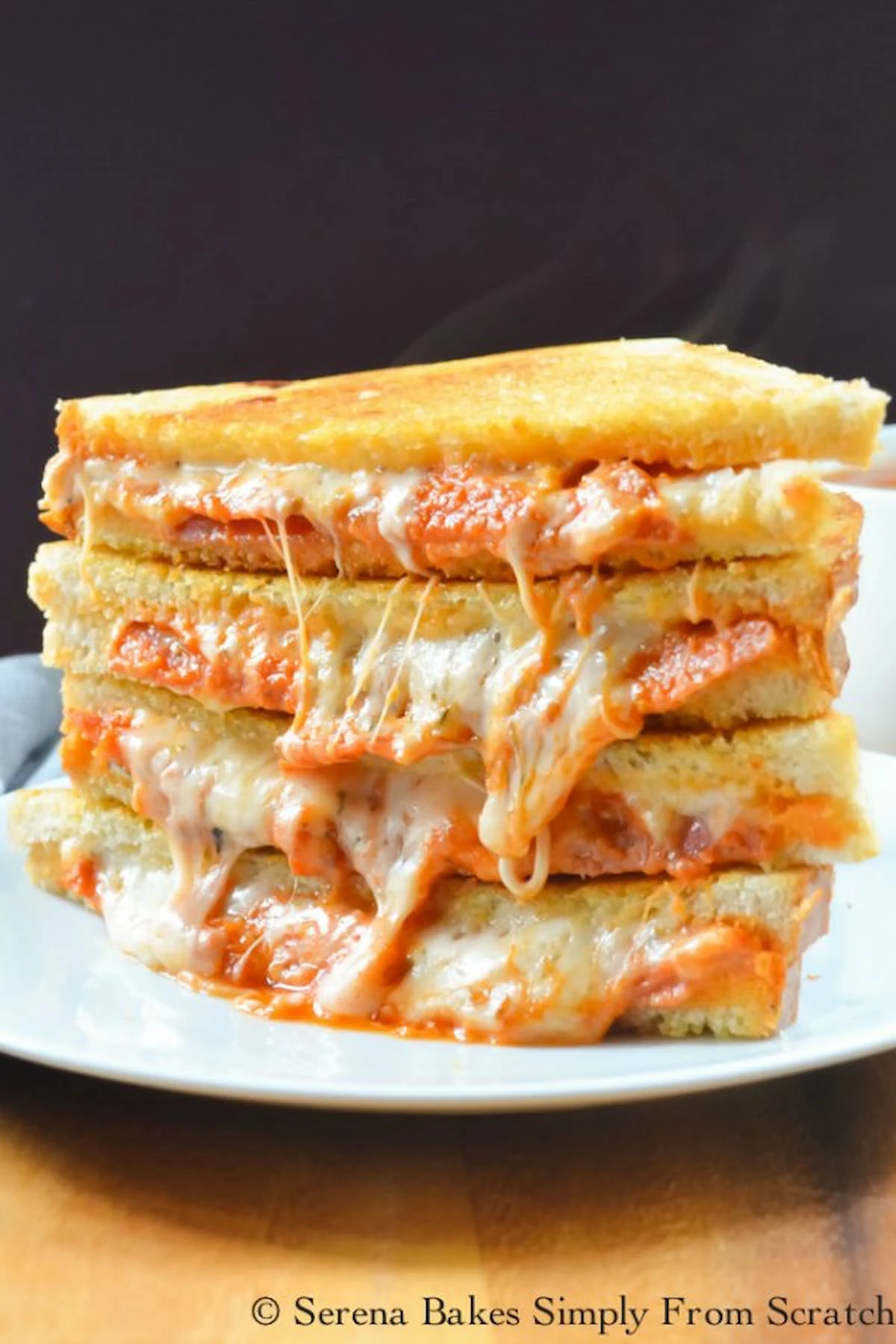 Pepperoni Pizza Grilled Cheese Sandwich stacked on a plate with Cheese pulling out of the sandwiches .
