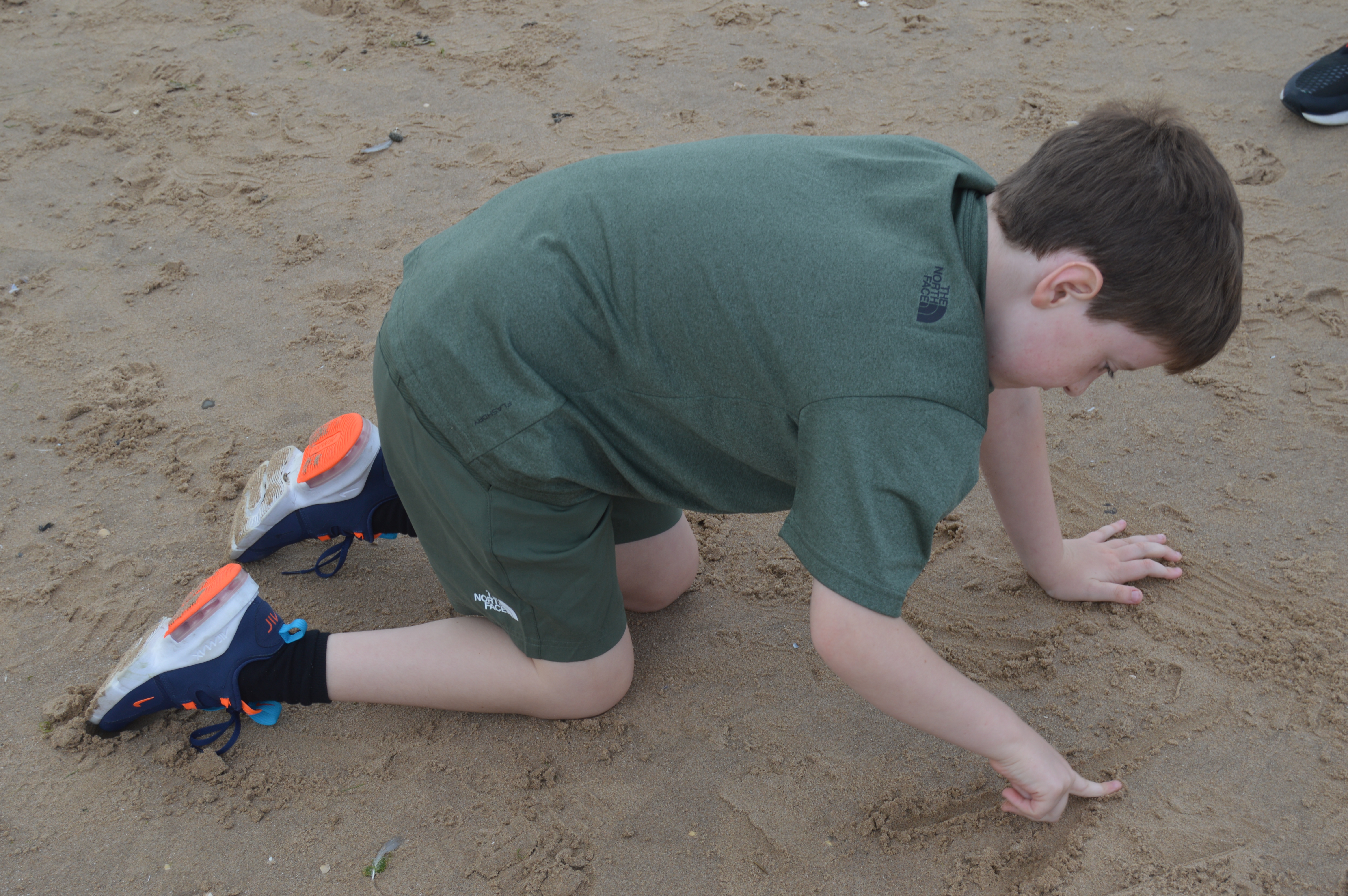Boy writing his name in the sand