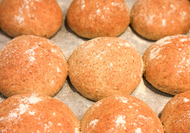 Close up of nine rolls, showing the warm brown glow and floury surface.