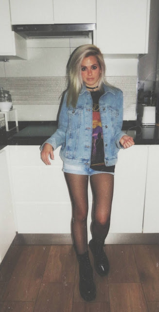 Estilo grunge con camiseta negra ancha con imagen del grupo The Doors, pantalón corto, medias de red pequeña, botas estilo militar y cazadora vaquera