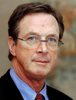 Foto de Michael Crichton, persona caucásica entrada en años, con gafas y ojos azules.