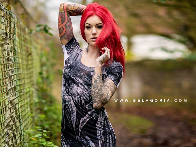 Foto de mujer peliroja posando en un parque, lleva tatuajes femeninos y muy vistosos