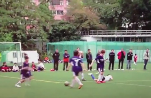 An U-12 Kitchee player holds his face after being kicked by his opponent form ESF