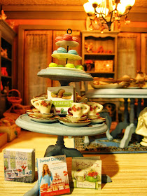 Modern miniature shabby chic shop three tier display of macarons, tea cup sets and cook books.