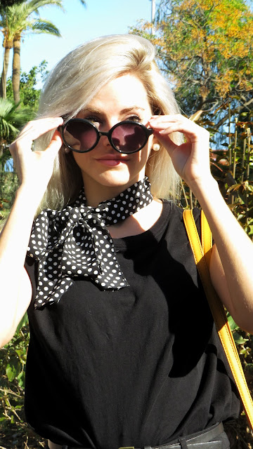 Alejandra Colomera con camiseta negra, pantalón formal negro, lazo en el cuello negro con lunares blancos y complementos mostaza