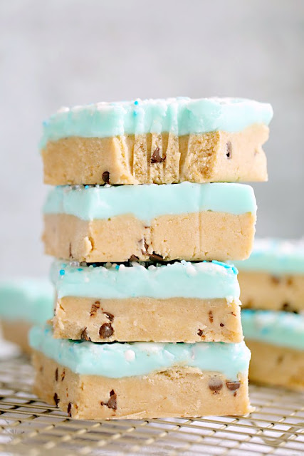 Get the taste of peanut butter chocolate chip cookie dough in these fun no-bake (and egg free) cookie dough bars. The white chocolate frosting takes them to the next level and a dusting of festive sprinkles is all you need to dress them up for a party. stack of peanut butter cookie bars