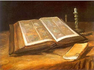 a bible sitting on a table with one small and large candle on the side