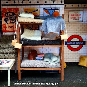 Miniature scene of a three-tier bunk in an underground shelter set up in a 1940s tube station.