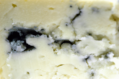 When a cheese is streaked with blue marks like this, we say it is ______. (image)