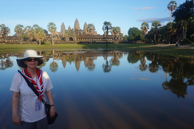 Me standing by Ankor Watt in Cambodia in a white top, hat and Girl Guiding Necker