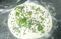 Flatten Butter Naan dough topped with coriander leaves and Nigella seeds