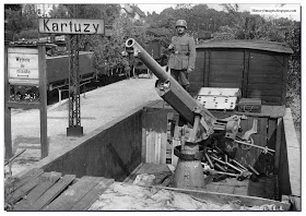 A German soldier stands guard over a captured Polish 75 mm anti-aircraft gun atop a railroad car in 1939