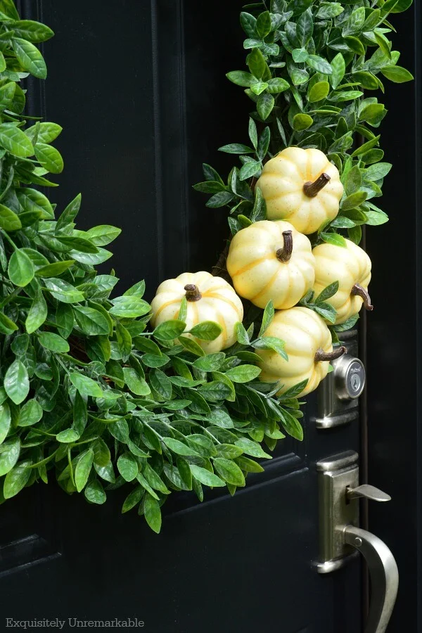 Simple Fall Boxwood Wreath With White Pumpkin On A Black Door