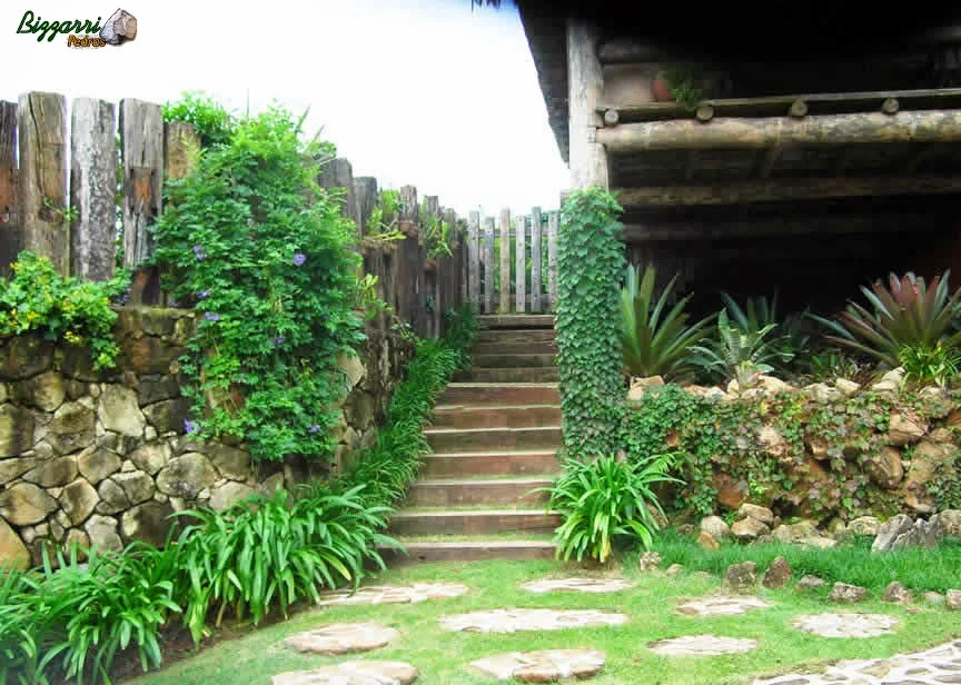 Caminhos de pedra rústica junto ao muro de pedra com a escada de dormentes de madeira.