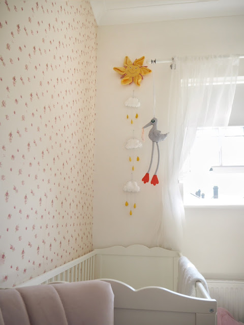 Nursery bedroom perfect for a baby girl toddler. Pink and swan ballet themed room with a sunburst mirror, feather lampshade, pom pom basket and liberty print rocking horse