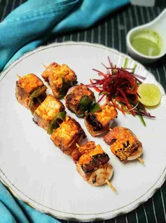 Paneer tikka serving in a garnished plate, green chutney in background