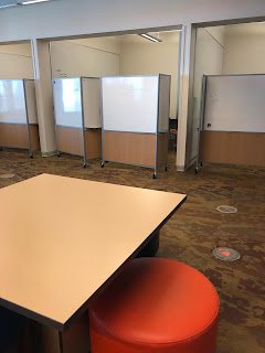 square table with movable stools and white boards on wheels in the background