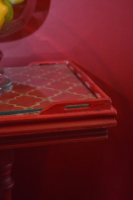 The corner of a red painted table with glass top