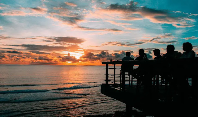 Watching sunset with a glass of cocktail at the Rock Bar bali, indonesia Watching sunset with a glass of cocktail at the Rock Bar bali, indonesia