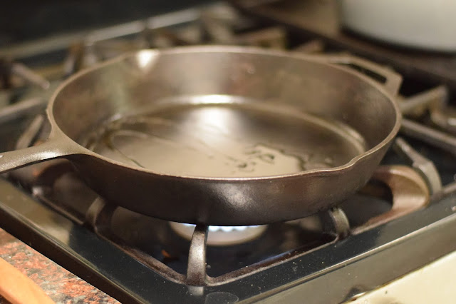 A cast iron skillet with oil in it over a medium/high heat.  