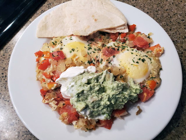 Plate of fried eggs, tomatoes with avocado mash