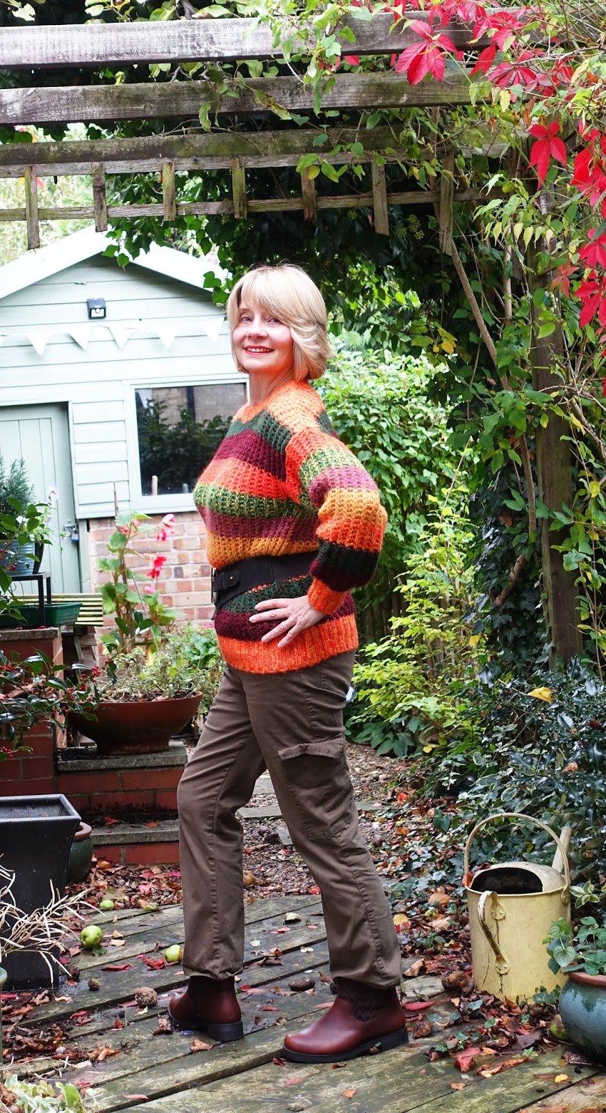 A flash of red Virginia Creeper for this autumn shot of over-50s blogger Gail Hanlon wearing Vionic Mystic Maple brown boots and an orange and green striped jumper