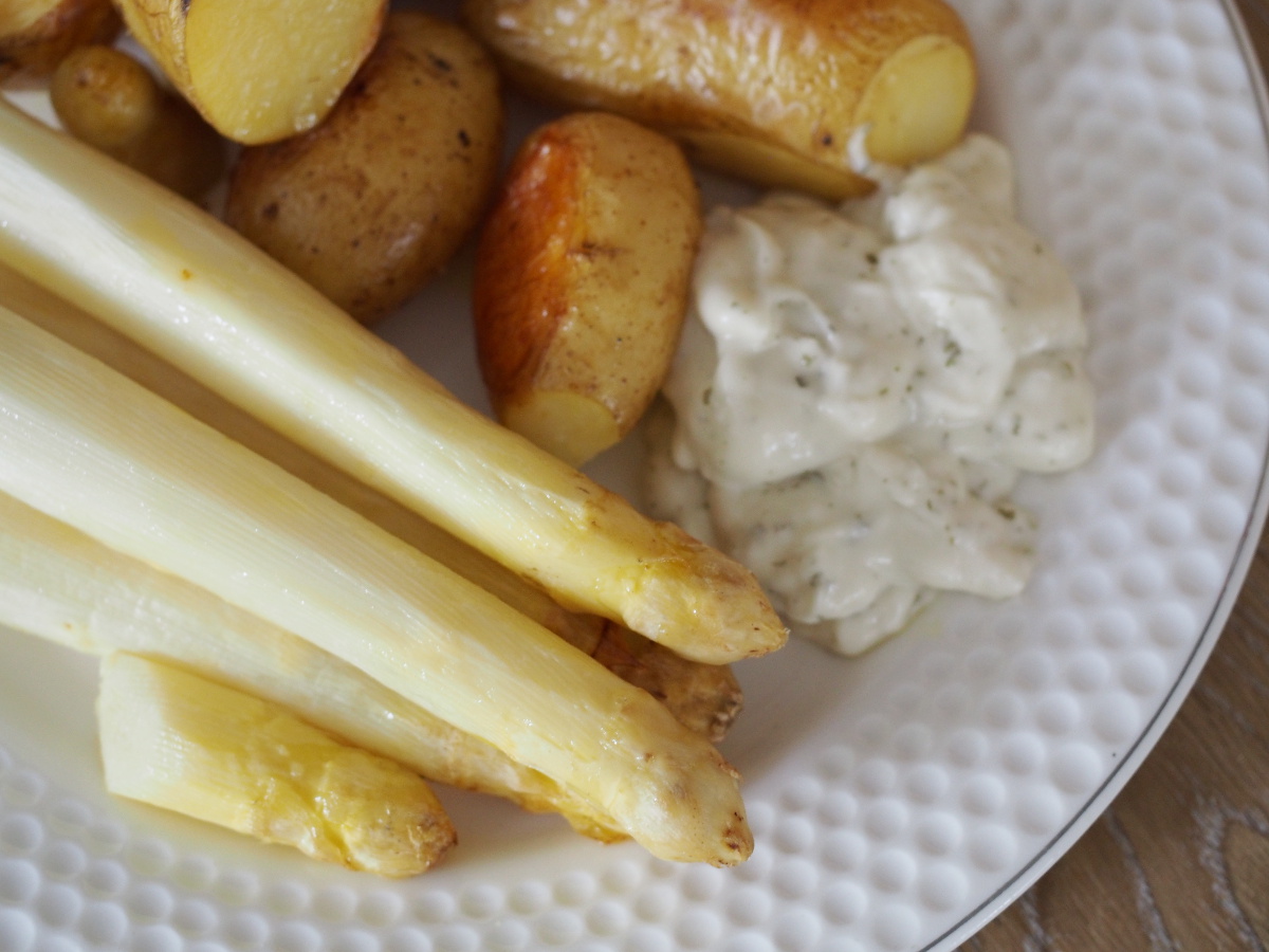 Weißser Spargel und Kartoffeln im Ofen zubereitet auf einem Teller mit etwas Remoulade an der Seite.