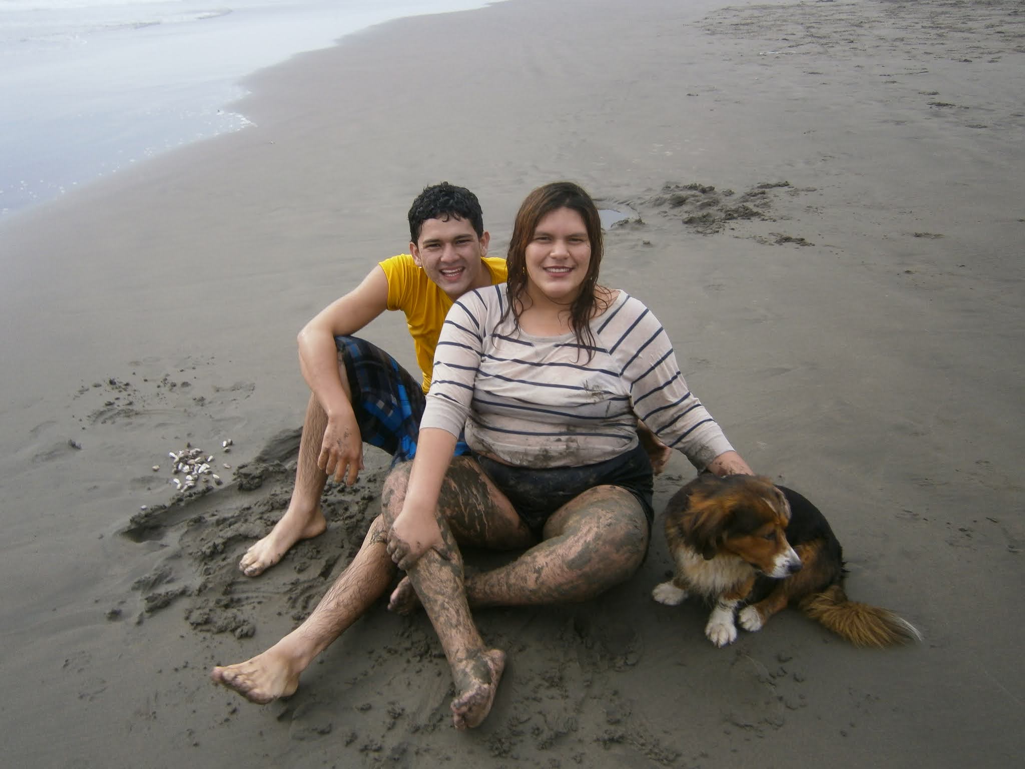 Pareja de enamorados posando para la foto en la orilla del mar y mascota