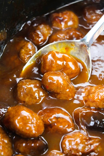 meatballs scooped by a spoon in a slow cooker.