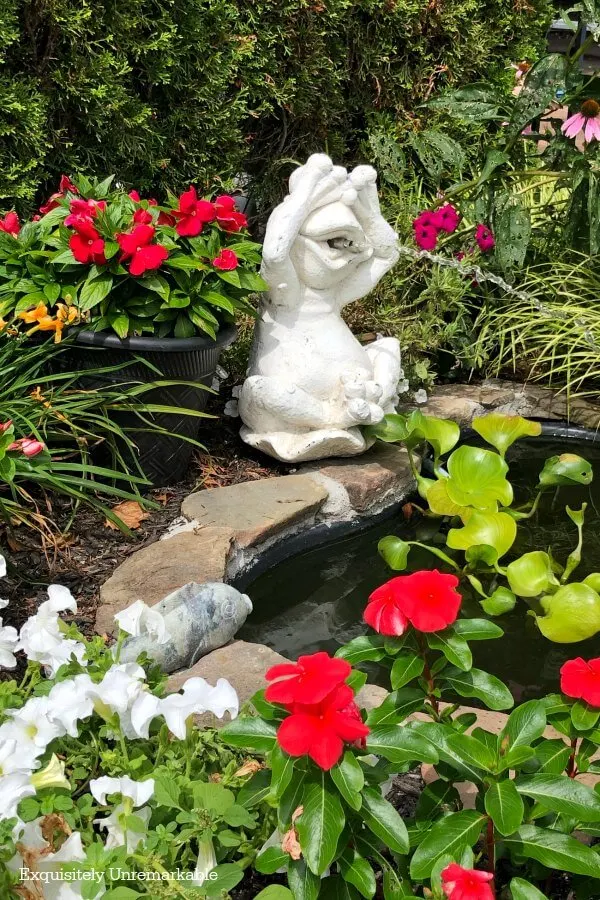 Frog Fountain Statue in Pond area with flowers