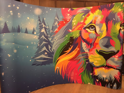 photo of mural showing a rainbow coloured lion against a background of a snowy forest