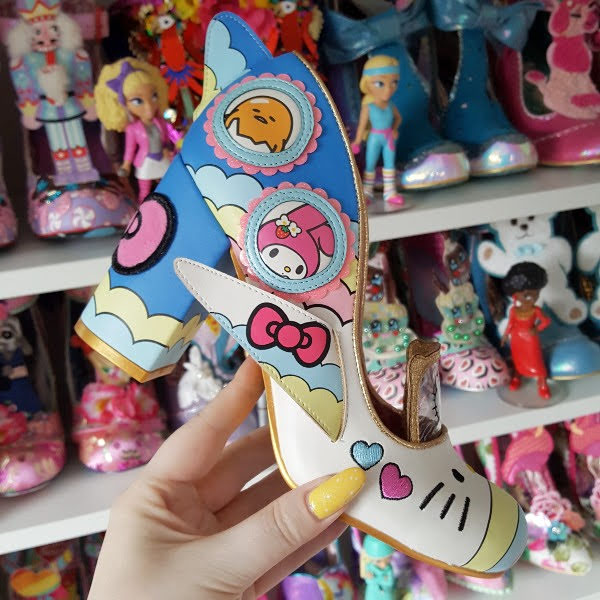 holding Hello kitty plane themed shoe in hand with shoe shelves in background
