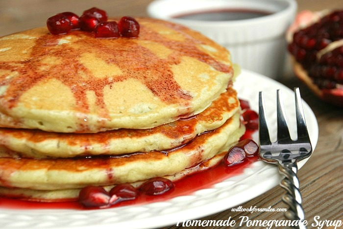 pancakes stacked up on a white plate with pomegranate syrup on top of it and pomegranate syrup.