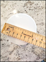 A ruler on top of lid of a glass bottle measuring diameter