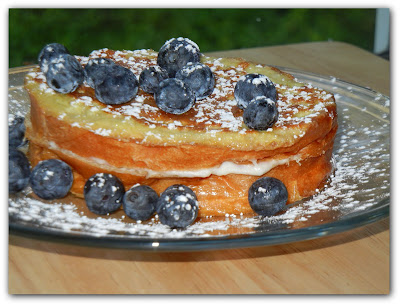 french toast on a plate with blueberries on top and around it 