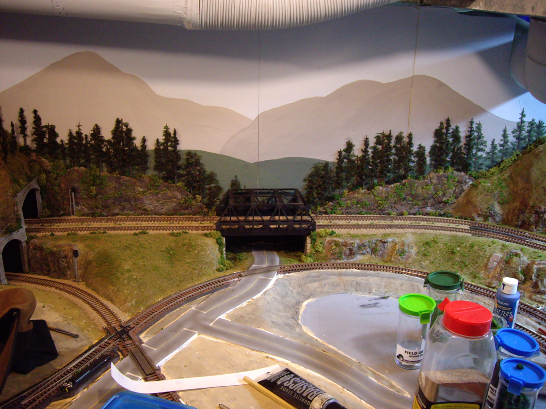 Background terrain and forest scene under construction around an upgraded warren-truss bridge