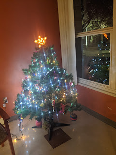 Tree with blue lights and a yellow lighted star. Also image in window and lighted outline of different tree