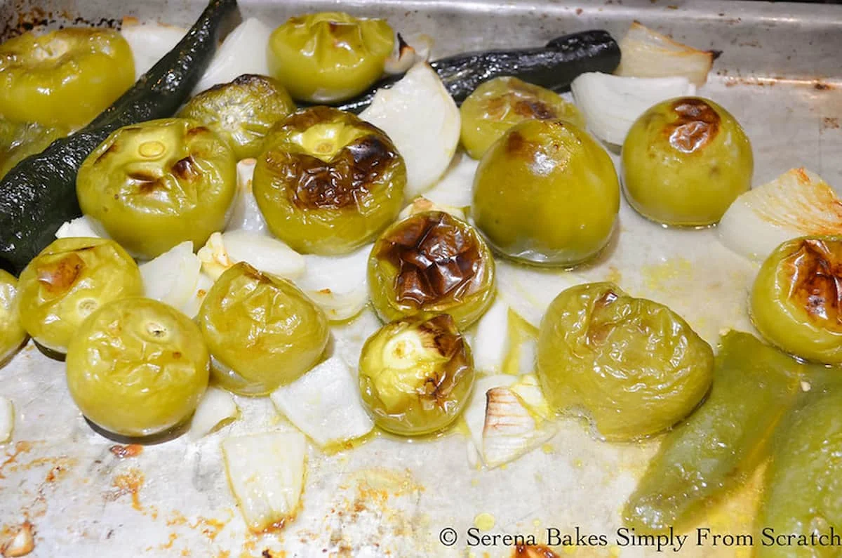 Roasted Tomatillos, Poblano Peppers, Jalapeños, Garlic, and Onion on a metal baking sheet.