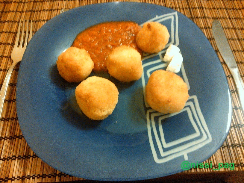 Una ración de croquetas de arroz con salsa de tomate