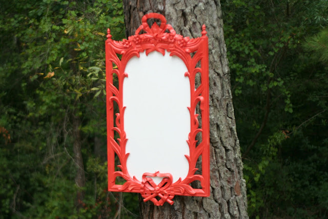 A vintage mirror that has a detailed, red wood frame