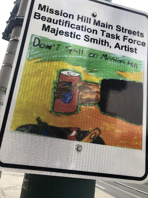 Sign: "MIssion Hill Main Streets Beautification Task Force - Majestic Smith Artist," picture of hand about to drop soda can into trashcan, words "Don't Spill on Mission Hill" written at top of illustration
