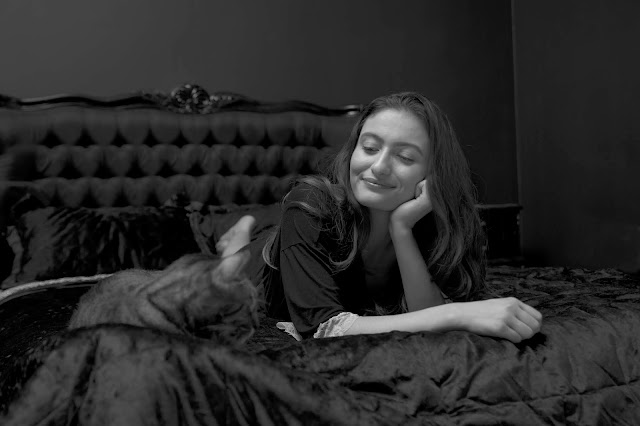 model smiling on a bed with a cat