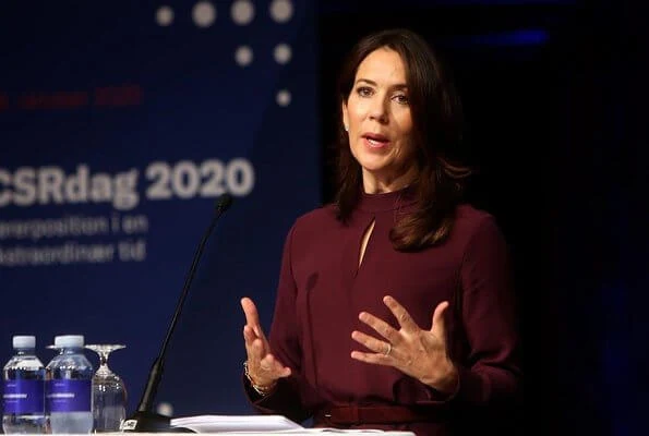 At the award ceremony, Crown Princess Mary wore a burgundy silk mock neck belted top and trousers, and grey cashmere wool long coat