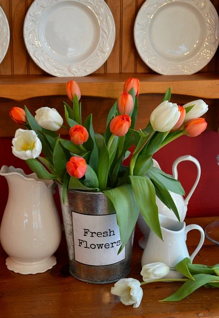 Orange tulips in a metal tin with white pitcher collection