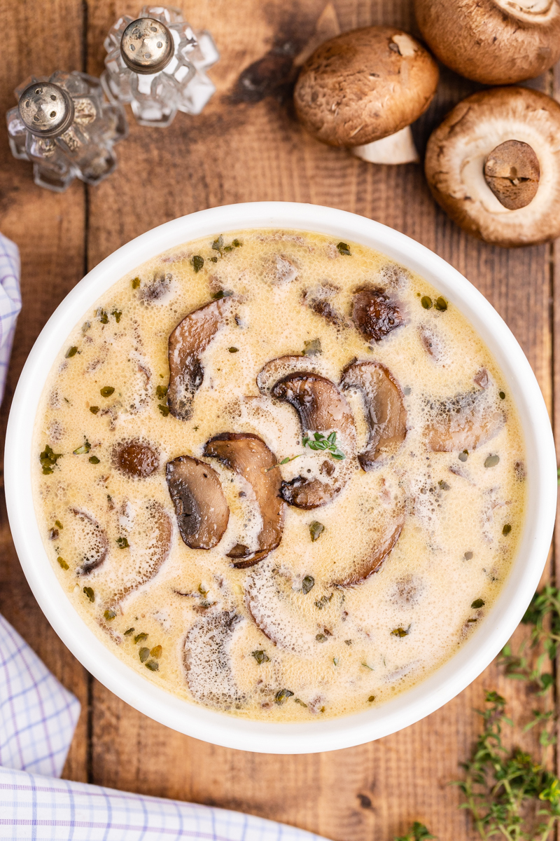 Overhead photo of Keto Cream of Mushroom Soup in a white soup bowl on a wooden table.