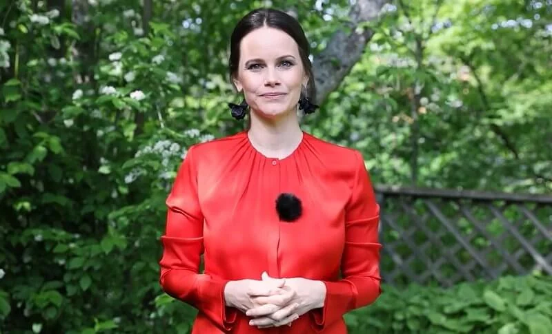 Princess Sofia wore a red silk satin, bell cuff long sleeve, gathered neck blouse, and black leaf earrings from Sanna Evers